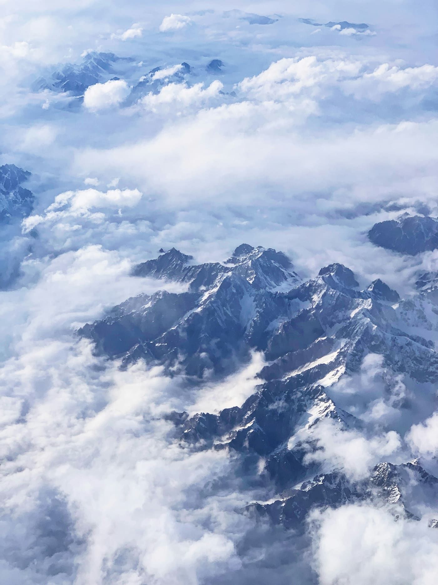 Aerial view of snow-covered mountain ranges above the clouds